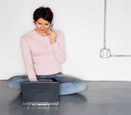 woman sitting on floor, using phone and laptop