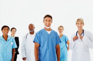 A team of doctors and nurses posing in front of a white wall