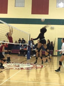 FNU Volleyball player in the air spiking ball over net