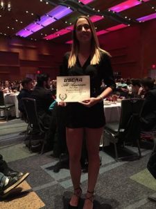 Volleyball player Bianca Baez holds up certificate at awards ceremony