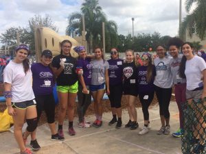FNU Lady Conquistadors volleyball team huddles together for a picture outside a playground