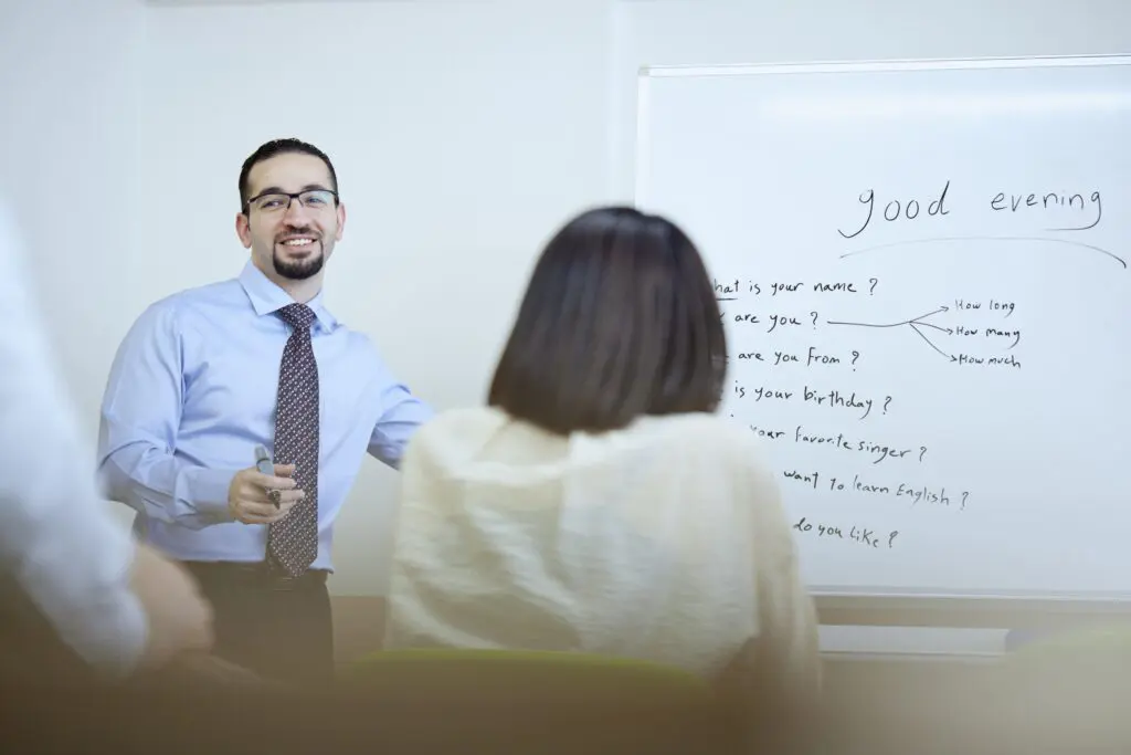 ESL teacher explaining English questions to students in a classroom.