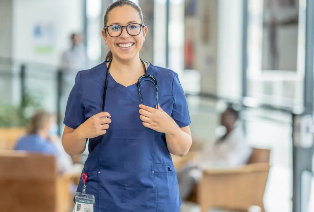 Smiling nurse in scrubs with a stethoscope, representing a healthcare professional pursuing a Master of Science in Nursing degree.