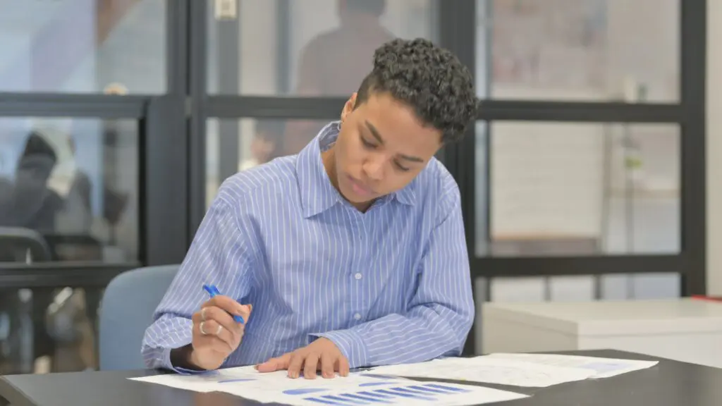 Person reviewing graphs and financial documents, illustrating entry-level business administration job tasks.