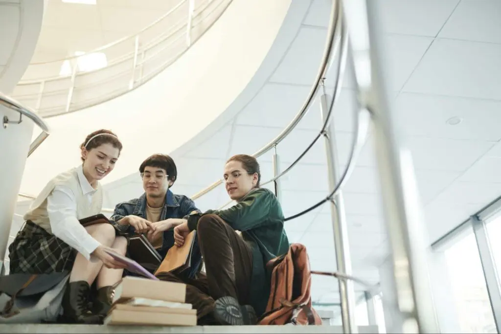 Group of undergraduate students studying together on campus stairs, representing collaboration in an undergraduate degree program.