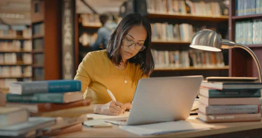 A female graduate studies student working on a culminating project in a library