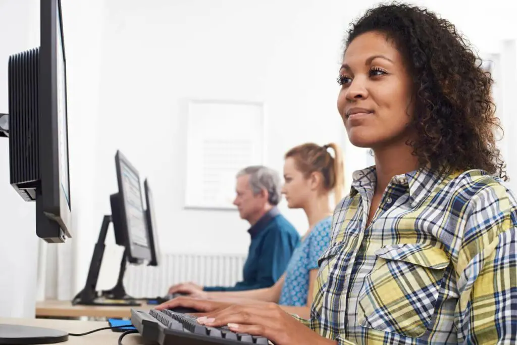 Adult students working on computers as part of online degree programs.