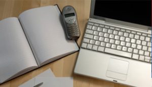Laptop and book with an old cellphone on top