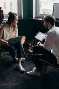 photo of couple talking while holding a laptop and an ipad