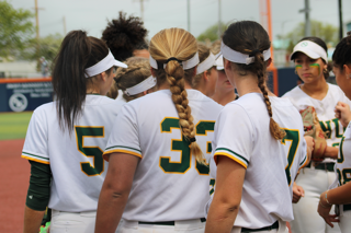 FNU softball players in a huddle.