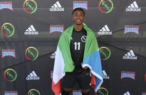 FNU men's soccer player Marcos Bakale holding Equatorial Guinea's flag.