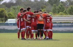 FNU men's soccer players in a huddle.