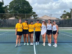 Group photo of FNU's women's tennis team in front of a net.