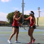Two women's tennis players high fiving.